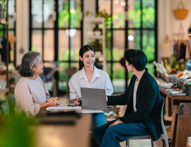 An Asian male investor and team meet with senior female owner at family business ceramic retail shop, negotiating and signing a partnership contract to expand retail and wholesale opportunities.